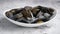 Shellfish raw mussels in ceramic white bowl, placed on stone gray background