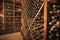 shelves with old wine bottles covered with dust aging at the vintage wine cellar at the winery
