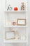 Shelves with red clock, wooden frameworks, bottle with seashells and candles