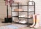 Shelving rack with stylish women`s shoes and accessories near white brick wall
