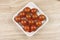 Sherry tomatoes in a porcelain bowl on wooden background