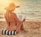 Shes a book-loving beauty. Rearview shot of an unidentifiable woman in a bikini reading on a tropical beach.