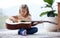 Shes found a new hobby. a little girl playing a guitar at home.