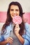 Shes got a real sweet tooth. Portrait of a beautiful young woman holding candy against a wall outside.