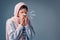 Shes got the sniffles. Studio shot of an attractive young woman blowing her nose while standing against a grey