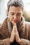 Shes hoping her prayers will get answered. a senior woman holding her hands together in prayer while sitting in her