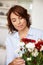 Shes a natural with flowers. a mature woman adjusting flowers in a vase at home.