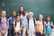 Shes so proud of her awesome students. A happy group of students standing at the blackboard with their teacher.