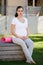 Shes still doing yoga every day. a young pregnant woman sitting with her yoga mat outside.