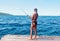Shes what you call the ultimate catch. Rearview shot of an attractive young woman standing on a pier and fishing near an