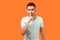 Shh, make silence please! Portrait of serious brunette man showing quiet gesture. isolated on orange background