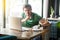 Shhh, Be quiet! Young angry businessman in green t-shirt sitting and working on laptop, looking at camera with finger on lips and