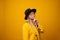 Shhh, gesturefinger near lips, mystery and secret. Stylish trending young woman in bright clothes on yellow background,