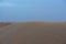 Shifting sand dunes in the Arabic desert with the sky in the background