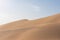 Shifting sand dunes in the Arabic desert with the sky in the background