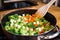 shifting steamed veggies around in a pan with a wooden spatula