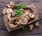 Shiitake edible mushrooms in the wooden plate on wooden table with herbs. Top view