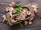Shiitake edible mushrooms in the wooden plate on wooden table with herbs. Top view