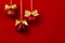 Shimmer balls with golden bows hang on ribbons in row on saturated red backdrop, copy space. Rich christmas background in modern.