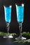 Shimmer edible glitter sparkling blue wine in two tall glasses on black background. Vertical format. Closeup