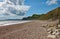 The shingle beach at Eype in Dorset on a sunny day, The sandstone cliffs of the Jurassic coast can be seen in the background