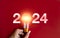 Shining 2024 calendar year numbers, neon style with creative trend light bulb holding by businessman\'s hand.