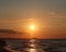 Shining golden, orange sunset reflected on surface of undulating Atlantic Ocean on summer evening