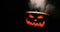 Shining Jack-O-Lantern. Halloween pumpkin with scary face smoke inside with flame isolated on the black background.