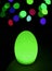 Shining neon green egg shaped table lamp with vibrant bokeh in background