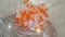 Shining, transparent, orange color crystal beads or gemstones in a glass bowl