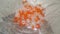 Shining, transparent, orange color crystal beads or gemstones in a glass bowl