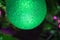 Shiny Christmas ball, on a blurred background of a green Christmas tree, part of the ball in the frame, open frame, close-up