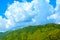 Shiny clouds with blue sky and green mountains