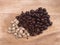 Shiny dark brown roasted tamarind seeds grouped with husk and kernels on wood chop board background