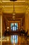 Shiny floor in long golden hallway with rainbow flags framing doorway at end of hall