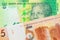 A shiny, green 10 rand bill from South Africa paired with a orange five ruble bank note from Belarus.