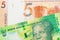 A shiny, green 10 rand bill from South Africa paired with a orange five ruble bank note from Belarus.