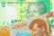 A shiny, green 10 rand bill from South Africa paired with a orange, plastic five dollar bill from New Zealand.