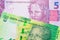 A shiny, green 10 rand bill from South Africa paired with a pink and purple five real bank note from Brazil.