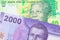 A shiny, green 10 rand bill from South Africa paired with a purple, plastic two thousand Chilean peso bank note.