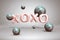 Shiny metal pink gold letters XOXO and bright flying blue balloons spheres on festive background with confetti for Valentines Day
