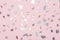 shiny metallic confetti on a pastel pink background