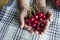 Shiny red cherry berries on a plate in the hands of a child, selective focus