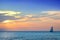 shiny sea and sailboat over cloudy sky and sun during sunset in Cozumel, Mexico