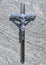 Shiny silver metal Christian cross, crucifix in the sun on grave stone background. Christian symbols, christianity and faith