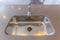 Shiny stainless steel sink and faucet on the gleaming kitchen countertop