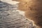 Shiny tropic sea wave on golden beach sand in sunset light