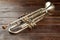 Shiny trumpet on brown wooden background.