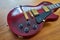 Shiny Wine Red Guitar With Golden Hardware on A Wooden Table Sid