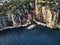 Ship from above aerial drone view. Blue deep water near the stony coast. people swimming around. Beautiful seacoast